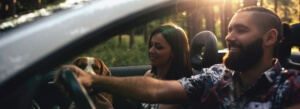 two people and dog driving through forest in a convertible - chip your car performance chips