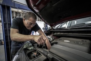 Man working under the hood of a car - Chip Your Car Audi Performance Chips Improve Gas Mileage